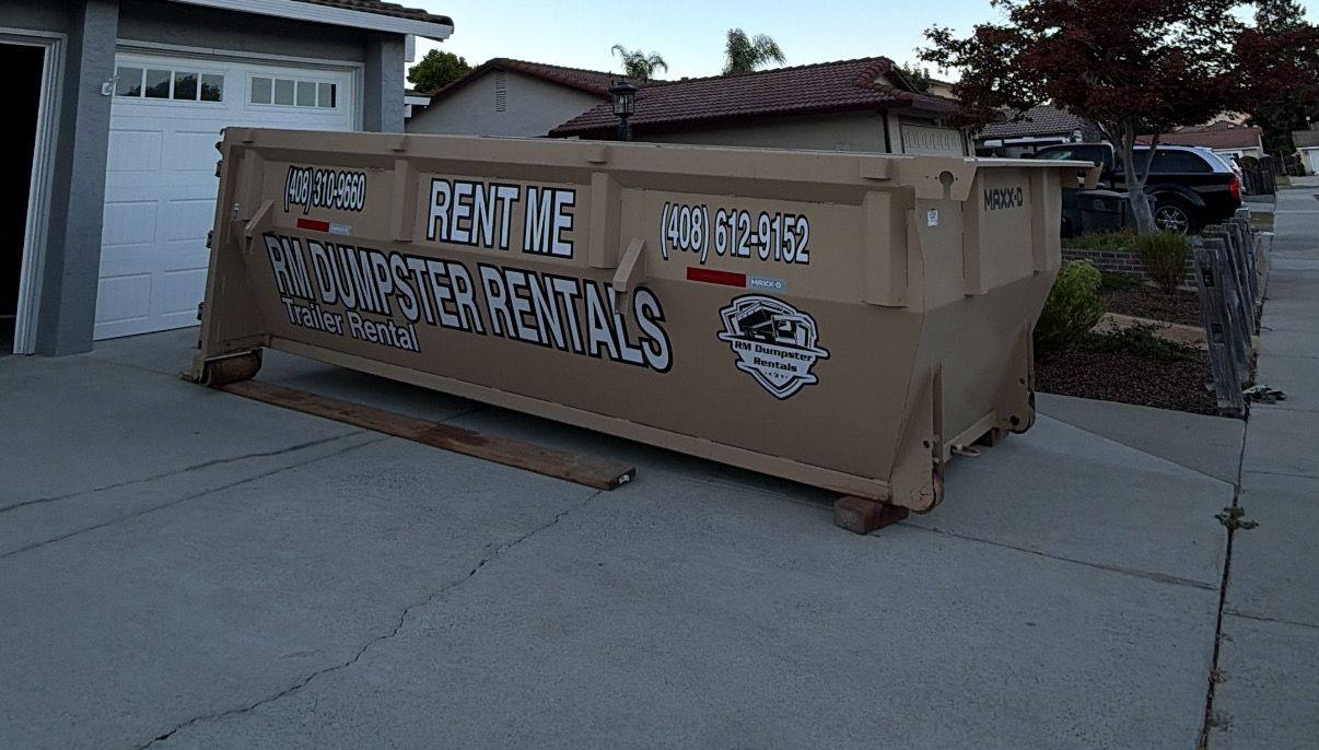 RM dumpster in a driveway at dusk