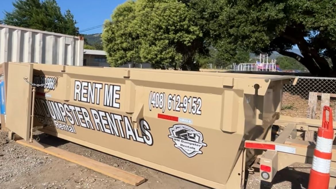 RM dumpster on a gravel job site with a traffic cone