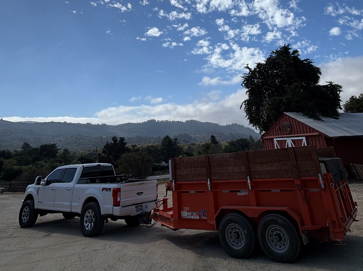 White pickup towing an orange dump trailer